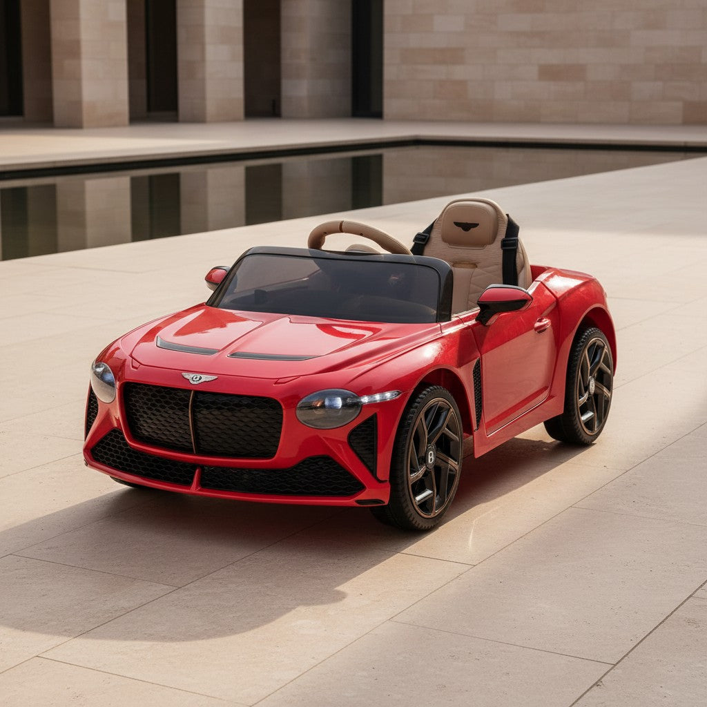 Bentley Red kids electric ride-on convertible car parked in a modern stone courtyard beside a reflecting pool, photographed in soft daylight.